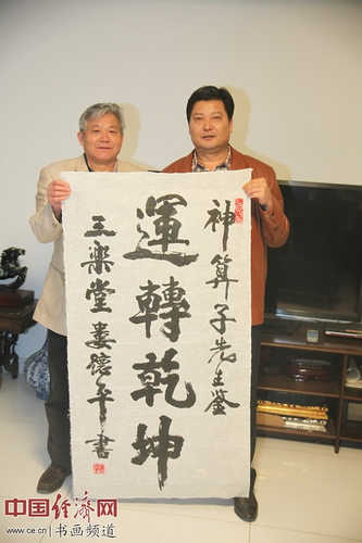 东西方艺术家协会主席娄德平(左)书法“神算子先生鉴,运转乾坤”赠与中国周易风水策划研究院院长张宝志(右) 中国经济网记者李冬阳摄