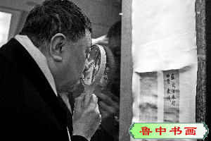 收藏家刘文杰用高倍放大镜观看《功甫帖》。